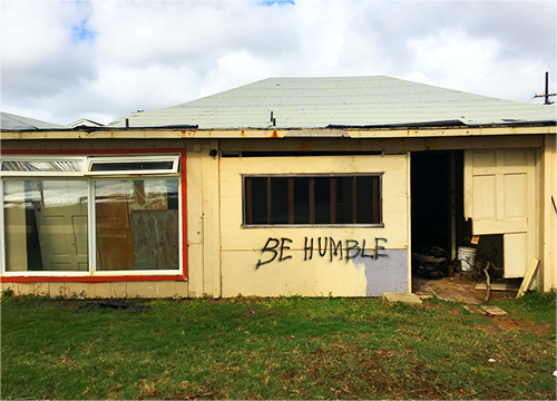 Horizontal color photograph of an abandoned house in Kauai, Hawaii, with graffiti.